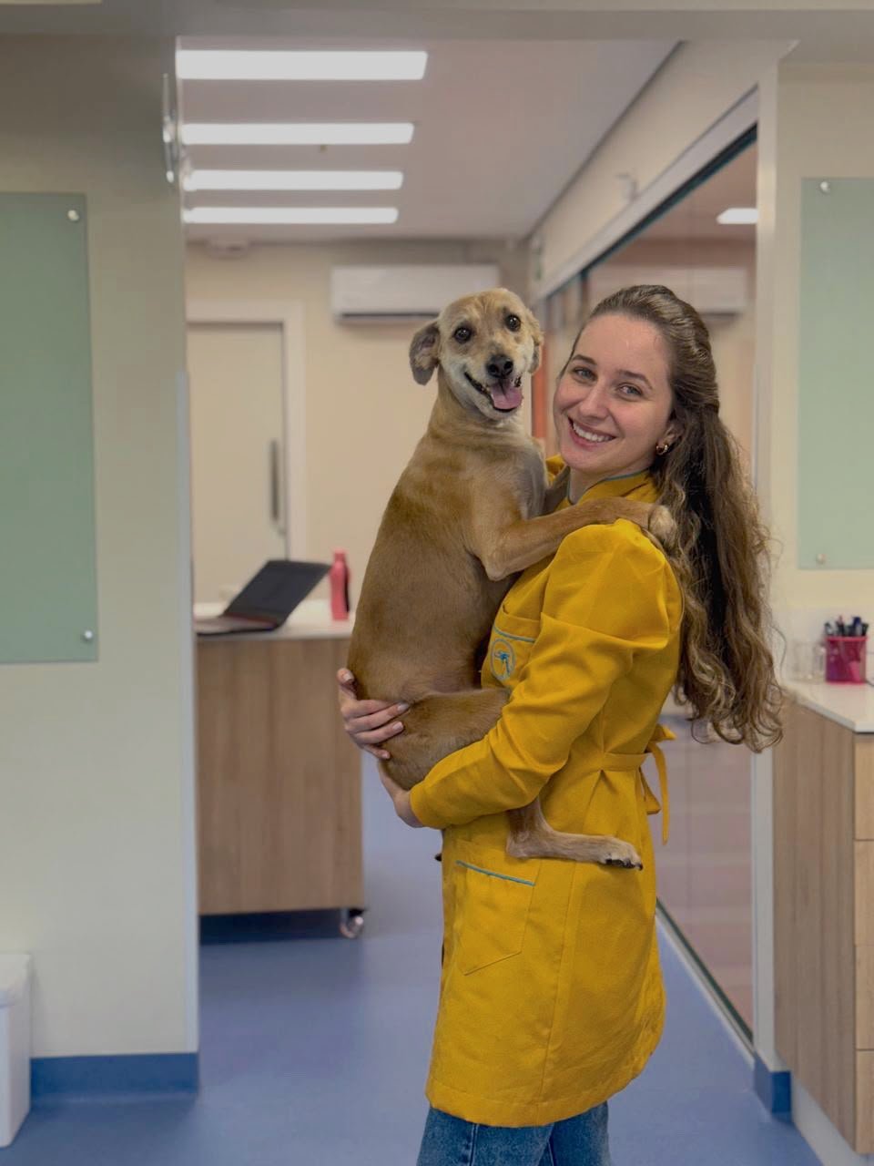 Dra. Emily Silvestre segurando um cão marrom no corredor da Alluvie.
